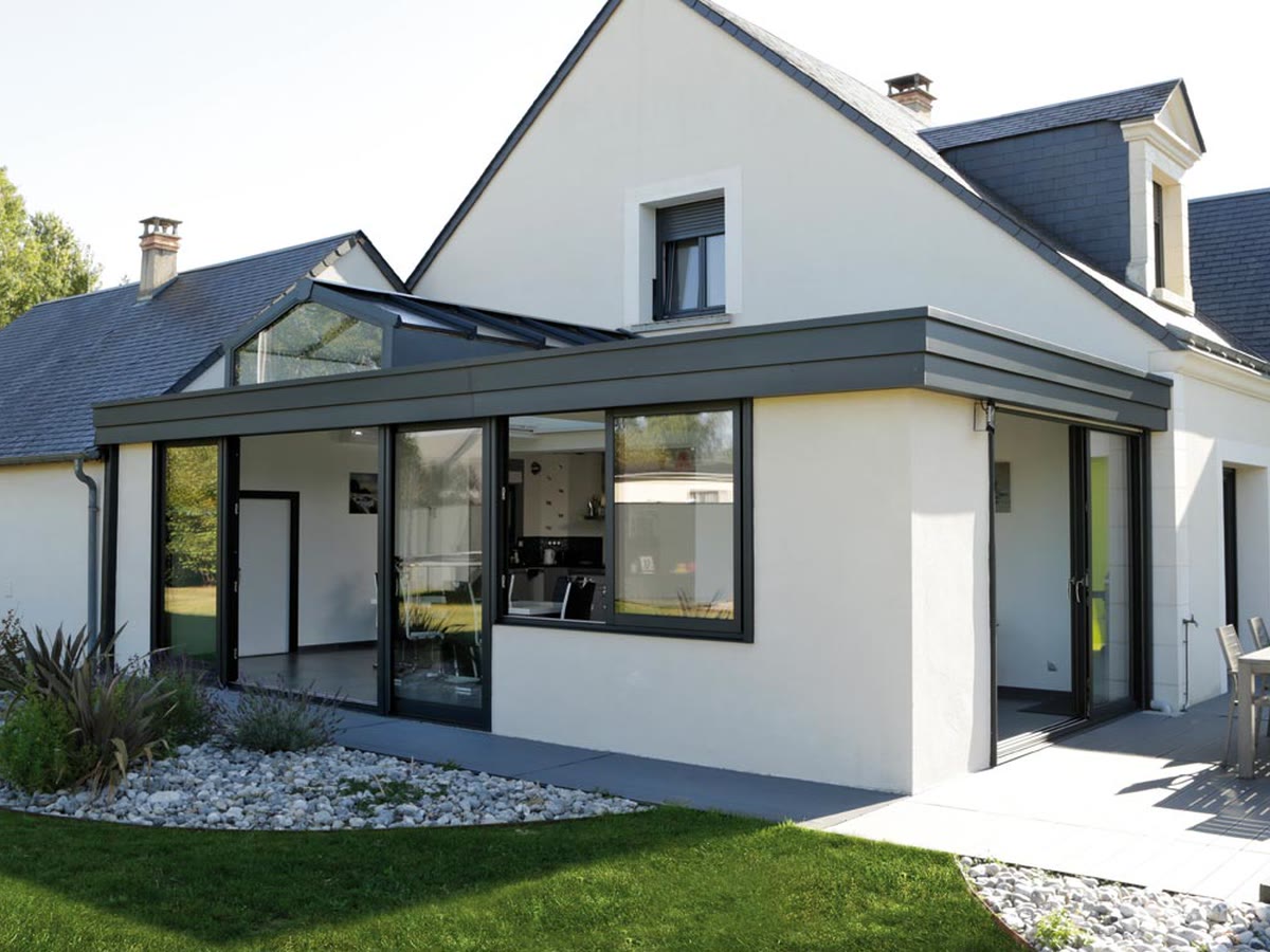 Extension véranda à toit plat prolongeant la maison et ouverte sur le jardin